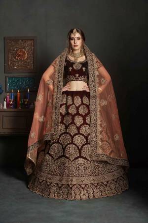 Get Ready For Your Big Day With This Latest Bridal Trend, Wearing This Heavy Designer Lehenga Choli In Maroon Color Paired With Contrasting Peach Colored Dupatta. This Heavy Embroidered Lehenga Choli Is Fabricated On Velvet Paired With Net Fabricated Dupatta. It Is Beautified With Heavy Embroidery and Stone Work. Buy Now
