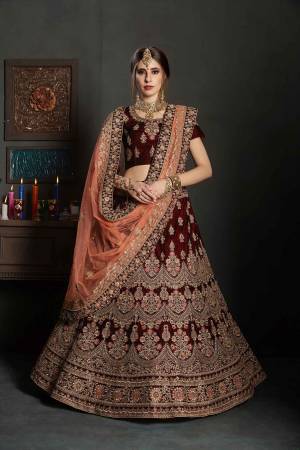 Here Is A Perfect Bridal Look For You In The Running Treand With This Heavy designer Lehenga Choli In Maroon Color Paired With Contrasting Peach Colored Dupatta. This Lehenga Choli Is Velvet Based Paired With Net Fabricated Dupatta.Its Fabric Also Ensures Superb Comfort Throughout The Gala