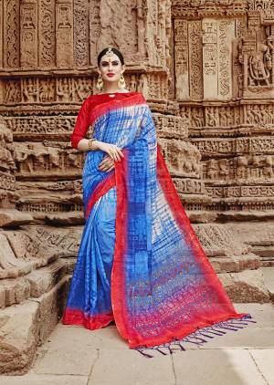 For Your Semi-Casuals. Grab This Beautiful Saree In Blue Color Paired With Contrasting Red Colored Blouse. This Saree And Blouse Are Fabricated On Khadi Silk Beautified Prints. It Is Light In Weight And Easy To Carry All Day Long. 