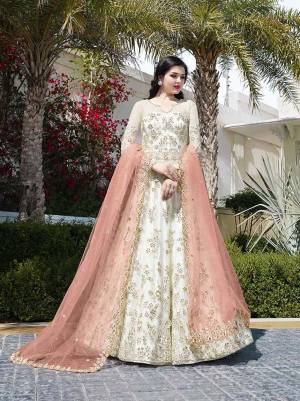 Simple And Elegant Looking Designer Floor Length Suit Is Here In Off-White Color Paired With Contrasting Peach Colored Dupatta. This Net Based Suit Is Beautified With Heavy Embroidery which It Making The Suit More Attractive. 