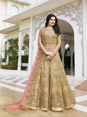 Here Is Another Rich And Elegant Looking Designer Floor Length Suit In Beige Color Paired With Contrasting Dark Peach Colored Dupatta. Its Heavy Embroidered Top Is Net Based Paired With Satin Bottom And Net Dupatta. Buy This Beautiful Suit Now.