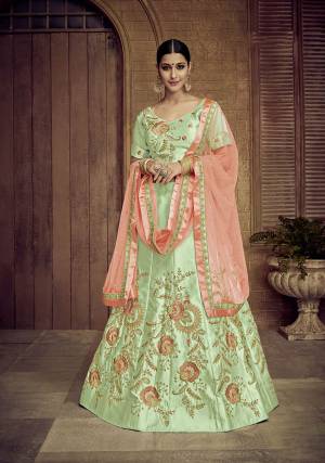 Here Is A Proper Traditional Color Pallete With This Heavy Designer Lehenga Choli In Light Green Color Paired With Contrasting Orange Colored Dupatta. Its Blouse And Lehenga Are Satin Silk Based Paired With Net Fabricated Dupatta. Its Fabric Also Ensures Superb Comfort Throughout The Gala. 