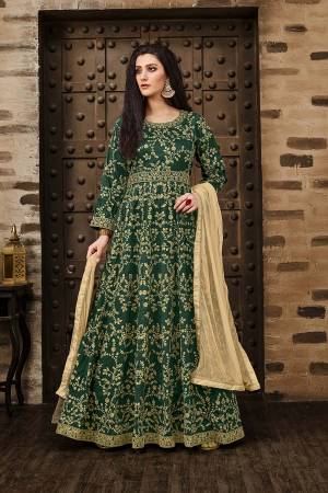Here Is A Beautiful Heavy Designer Floor Length Suit In Dark Green Color Paired With Beige Colored Dupatta. Its Heavy Embroidered Floor Length Top Is Fabricated On Tafeta Silk Paired With Santoon Bottom And Net Fabricated Dupatta. Buy Now.