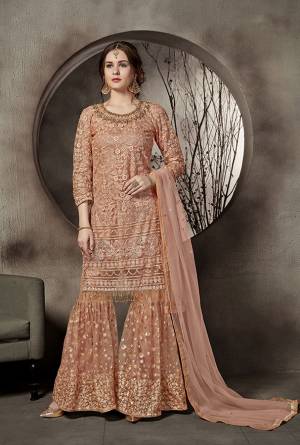 This Summer Is About Subtle Shades And Pastel Play, Grab This Heavy Designer Sharara Suit In Dark Peach Color. This Pretty Suit Is Net Based. Its Top And Bottom Are Beautified With Heavy Tone To Tone Embroidery Which Gives A Heavy Rich And Subtle Look To Your Personality. Buy Now.