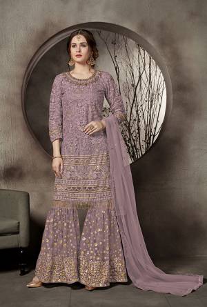 This Summer Is About Subtle Shades And Pastel Play, Grab This Heavy Designer Sharara Suit In Mauve Color. This Pretty Suit Is Net Based. Its Top And Bottom Are Beautified With Heavy Tone To Tone Embroidery Which Gives A Heavy Rich And Subtle Look To Your Personality. Buy Now.