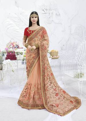 A Must Have Shade In Every Womens Wardrobe Is Here With This Heavy Designer Saree In Peach Color Paired With Contrasting Red Colored Blouse. This Pretty Saree Is Net Based Beautified With Attractive Work Paired With Art Silk Fabricated Blouse. 