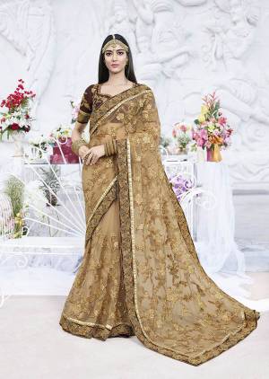 Flaunt Your Rich And Elegant Taste Wearing This Heavy Designer Saree In Beige Color Paired With Brown Colored Blouse. This Heavy Tone To Tone Embroidered Saree Is Fabricated On Net Paired With Art Silk Fabricated Blouse. 