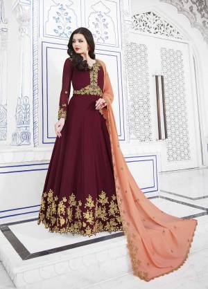 Royal Looking Designer Floor Length Suit Is Here In Maroon Color Paired With Contrasting Dark Peach Colored Dupatta. Its Top And Dupatta Are Fabricated On Georgette Paired With Santoon Bottom. It Is Beautified With Heavy Jari Embroidery And Stone Work. 