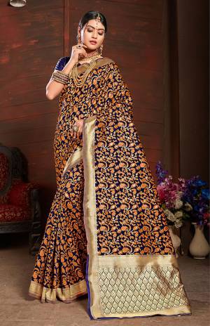 Add This Very Pretty Silk Based Saree To Your Wardrobe In Orange With A Base OF Navy Blue Color. This Saree Is Fabricated On Banarasi Art Silk Paired With Art Silk Fabricated Blouse. It Is Beautified With Small Floral Weave All Over It. 