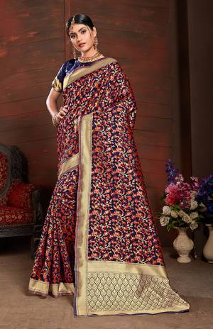 Add This Very Pretty Silk Based Saree To Your Wardrobe In Red With A Base OF Navy Blue Color. This Saree Is Fabricated On Banarasi Art Silk Paired With Art Silk Fabricated Blouse. It Is Beautified With Small Floral Weave All Over It. 