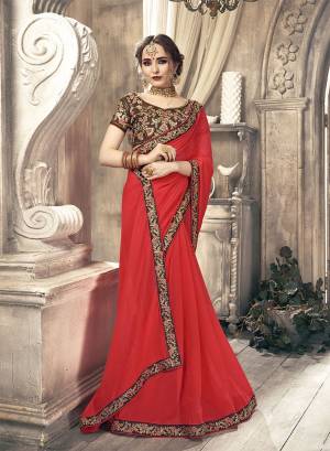 Grab This Very Beautiful And Attractive Looking Designer Saree In Heavy Blouse concept. This Chiffon Based Saree Is In Crimson Red Color Paired With Brown Colored Art Silk Fabricated Blouse. Buy This Saree Now.