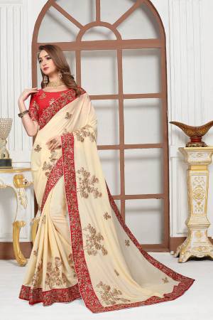 Get Ready For The Upcoming Festive And Wedding Season With This Heavy Designer Saree In Cream Color Paired With Red Colored Blouse. This Saree Is Fabricated On Chiffon Satin Paired With Art Silk Fabricated Blouse. It Is Beautified With Attractive Embroidery With Heavy embroidered Lace Border. 