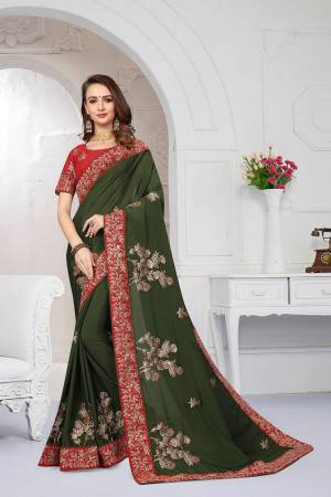 Get Ready For The Upcoming Festive And Wedding Season With This Heavy Designer Saree In Olive Green Color Paired With Red Colored Blouse. This Saree Is Fabricated On Chiffon Satin Paired With Art Silk Fabricated Blouse. It Is Beautified With Attractive Embroidery With Heavy embroidered Lace Border. 