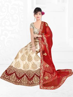 Flaunt Your Rich And Elegant Taste With Some Subtle Color Pallet In Your Bridal Wear. Grab This Heavy Designer Lehenga Choli In Cream Color Paired With Red Colored Dupatta. Its Blouse Are Lehenga are Satin Silk Based Paired With Net Fabricated Dupatta. 
