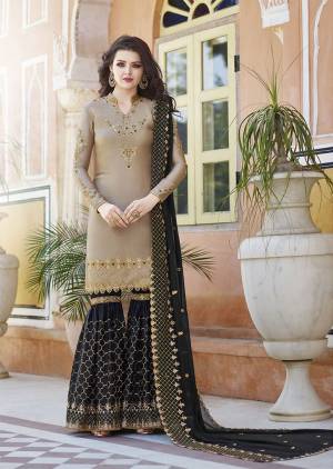 Flaunt Your Rich And Elegant Taste Wearing This Heavy Designer Sharara Suit In Beige And Black Color Which Is Trending This Season. Its Heavy Embroidered Satin based Top And Bottom Are Paired With Georgette Based Dupatta. Buy This Designer Piece Now.