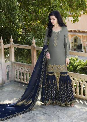 Flaunt Your Rich And Elegant Taste Wearing This Heavy Designer Sharara Suit In Grey And Navy Blue Color Which Is Trending This Season. Its Heavy Embroidered Satin based Top And Bottom Are Paired With Georgette Based Dupatta. Buy This Designer Piece Now.