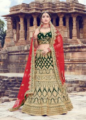Here Is A New And Unique Color Pallete For The Bridal Wear Is Here With This Heavy Designer Lehenga Choli In Dark Green Color Paired With Contrasting Rani Pink Colored Dupatta. This Lehenga And Blouse are Fabricated On Velvet Paired With Net Fabricated Dupatta. 
