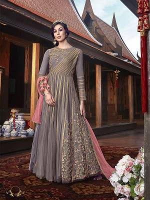 New And Unique Styled Indo-Western Dress Is Here In Grey Color Paired With Contrasting Pink Colored Dupatta. Its Pretty Gown Is Fabricated On Satin Georgette With Net Fabricated Embroidered Jacket Which Has Opening At The Side Front With Tassels, Paired With Santoon Bottom And Net Dupatta.