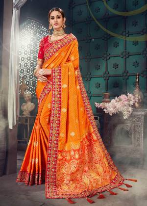 Here Is An Attractive Looking Heavy Designer Saree In Orange Color Paired With Contrasting Red Colored Blouse. This Saree Is Fabricated On Jacquard Silk Paired With Cotton Slub Fabricated Blouse. This Saree And Blouse Are Beautified With Heavy Embroidery. 