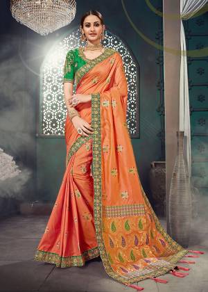 Here Is An Attractive Looking Heavy Designer Saree In Orange Color Paired With Contrasting Green Colored Blouse. This Saree Is Fabricated On Jacquard Silk Paired With Cotton Slub Fabricated Blouse. This Saree And Blouse Are Beautified With Heavy Embroidery. 