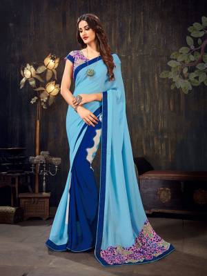 Here Is A Pretty Comfortable And Light Weight Saree In Blue And Pink Color Fabricated On Chiffon. Its Blouse Is Beautified With Prints All Over And The Saree Has A Printed Patch Over The Pallu. 