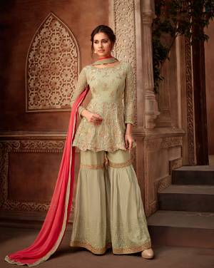 This Season Is About Subtle Shades And Pastel Play, So Grab This Designer Sharara Suit In Pastel Green Color Paired With Contrasting Crimson Red Colored Dupatta. Its Heavy Embroidered Top Is Georgette Based Paired With Stitched Santoon Fabricated sharara And Chiffon Fabricated Dupatta. 