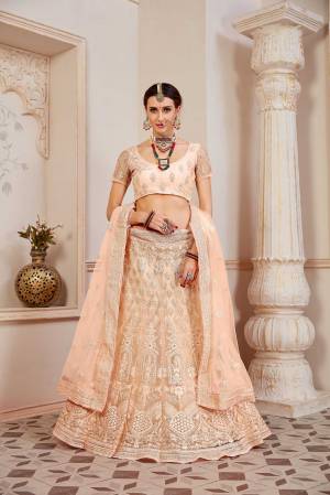 This Wedding Season Be The Most Sensational Diva Wearing This Heavy Designer Lehenga Choli In Light Peach Color. This Pretty Blouse, Lehenga And Dupatta Are Fabricated On Net Beautified With Tone To Tone Coding And Resham Embroidery With Stone Work. Buy This Designer Piece Now.