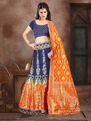 Shine Bright In This Very Beautiful Designer Lehenga Choli In Navy Blue Color Paired With Contrasting Orange Colored Dupatta. This Lehenga Choli Is Fabricated On Banarasi Jacquard Silk Beautified With Weave All Over. 