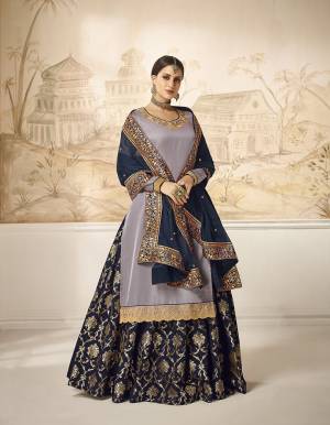 Choose Your Indo-Western Style As Per Occasion And You Can Get Its Bottom Stitched As Skirt Or Plazzo. Its Pretty Top Is In Mauve Grey Color Paired With Contrasting Navy Blue Colored Bottom And Dupatta. Its Top Is Fabricated On Satin Silk Paired With Jacquard Silk Bottom And Georgette Silk Fabricated Dupatta. Buy This Lovely Designer Piece Now.