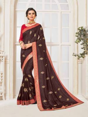 Enhance Your Personality Wearing This Designer Silk Based Saree In Brown Color Paired With Contrasting Red Colored Blouse. Its Rich Fabric Is Light Weight And Durable And Gives A Royal Look To Your Personality. 