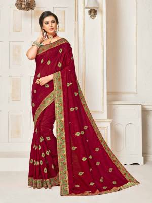 Shine Bright Wearing This Designer Silk Based Saree In Maroon Color Paired With Contrasting Green Colored Blouse. It Is Beautified With Embroidered Small Butti With Jacqurd Lace Border All Over, Buy Now.