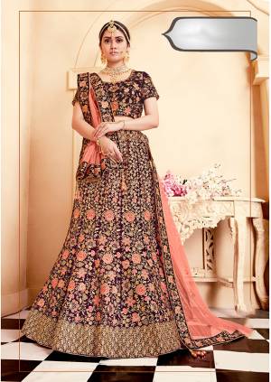 Get Ready For Your D-Day With This Heavy Designer Bridal Lehenga Choli In Wine Color Paired With Contrasting Dark Peach Colored Dupatta. Its Heavy Embroidered Blouse And Lehenga Are Fabricated On Velvet Paired With Net Fabricated Dupatta. 