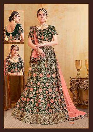 Get Ready For Your D-Day With This Heavy Designer Bridal Lehenga Choli In Dark Green Color Paired With Contrasting Dark Peach Colored Dupatta. Its Heavy Embroidered Blouse And Lehenga Are Fabricated On Velvet Paired With Net Fabricated Dupatta. 