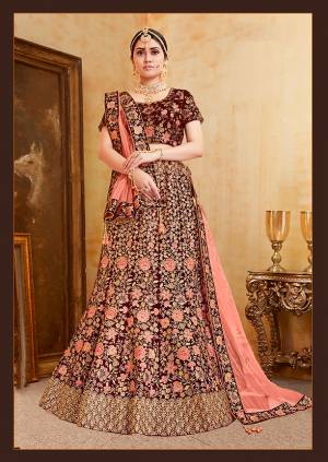 Be The Prettiest Bride Wearing This Very Beautiful And Heavy Embroidered Designer Bridal Lehenga Choli In Maroon Color Paired With Contrasting Dark Peach Colored Dupatta. This Lehenga Choli Is Velvet Based Paired With Net Fabricated Dupatta. Buy This Beautiful Lehenga Choli Now.