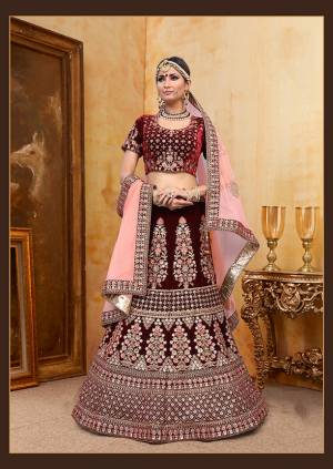 Get Ready For Your D-Day With This Heavy Designer Bridal Lehenga Choli In Maroon Color Paired With Contrasting Baby Pink Colored Dupatta. Its Heavy Embroidered Blouse And Lehenga Are Fabricated On Velvet Paired With Net Fabricated Dupatta. 