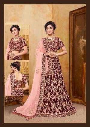 Be The Prettiest Bride Wearing This Very Beautiful And Heavy Embroidered Designer Bridal Lehenga Choli In Maroon Color Paired With Contrasting Light Peach Colored Blouse. This Lehenga Choli Is Velvet Based Paired With Net Fabricated Dupatta. Buy This Beautiful Lehenga Choli Now.