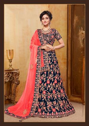 Get Ready For Your D-Day With This Heavy Designer Bridal Lehenga Choli In Dark Blue Color Paired With Contrasting Coral Red Colored Dupatta. Its Heavy Embroidered Blouse And Lehenga Are Fabricated On Velvet Paired With Net Fabricated Dupatta. 