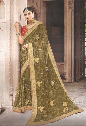 Must Have Shade In Every Womens Wardrobe Is Here With This Designer Piece In Olive Green Colored Saree Paired With Contrasting Red Colored Blouse. This Pretty Saree Is Fabricated On Georgette Paired With Art Silk Fabricated Blouse. 