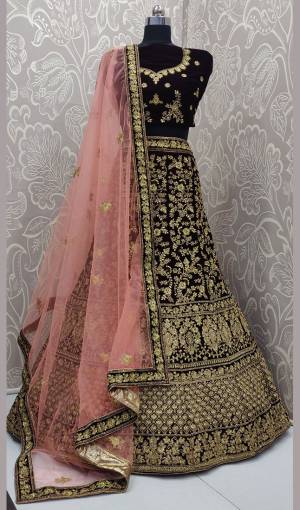 Here Is A Heavy Embroidered Designer Bridal Lehenga Choli For Your D-Day. This Heavy Velvet Based Lehenga Choli Is In Dark Maroon Color Paired With Baby Pink Colored Net Fabricated Dupatta. It Is Beautified With Heavy Jari And Coding Embroidery With Stone Work. 