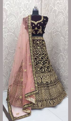 Here Is A Heavy Embroidered Designer Bridal Lehenga Choli For Your D-Day. This Heavy Velvet Based Lehenga Choli Is In Dark Wine Color Paired With Baby Pink Colored Net Fabricated Dupatta. It Is Beautified With Heavy Jari And Coding Embroidery With Stone Work. 