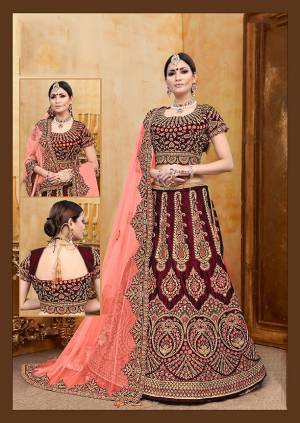 Be The Prettiest Bride Wearing This Very Beautiful And Heavy Embroidered Designer Bridal Lehenga Choli In Maroon Color Paired With Contrasting Dark Peach Colored Dupatta. This Lehenga Choli Is Velvet Based Paired With Net Fabricated Dupatta. Buy This Beautiful Lehenga Choli Now.