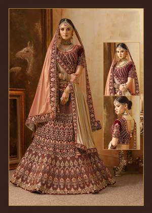 Be The Prettiest Bride Wearing This Very Beautiful And Heavy Embroidered Designer Bridal Lehenga Choli In Maroon Color Paired With Contrasting Peach Colored Dupatta. This Lehenga Choli Is Velvet Based Paired With Net Fabricated Dupatta. Buy This Beautiful Lehenga Choli Now.