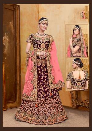 Get Ready For Your D-Day With This Heavy Designer Bridal Lehenga?Choli In Wine Color Paired With Contrasting Pink Colored Dupatta. Its Heavy Embroidered Blouse And Lehenga Are Fabricated On Velvet Paired With Net Fabricated Dupatta