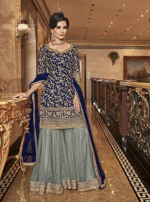 Bold And Elegant Color Pallete IS Here With This Designer Sharara Suit In Navy Blue Colored Top And Dupatta Paired With Contrasting Grey Coloree Bottom. Its Top, Bottom And Dupatta Are Fabricated On Net Beautified With Heavy Embroidery. Buy Now.
