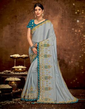 Exude ethereal elan and walk down with glorious aura in this beautiful grey and blue saree. Drape it in a regal rajwadi style drape and look like a royalty. 