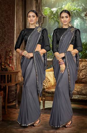 Here Is A Royal Looking Designer Saree In Grey Color Paired With Black Colored Blouse. This Saree Is Fabricated On Lycra Paired With Art Silk Fabricated Blouse. It Is Bautified With Hand Work Patch And Fancy Lace Border. 