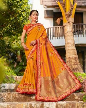 Celebrate This Festive Season Wearing This Heavy Designer Saree In Musturd Yellow Color Paired With Contrasting Orange Colored Blouse. This Saree And Blouse are Silk Based Giving You A Proper Traditional Look. 
