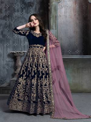 Get Ready For The Upcoming Wedding And Festive Season Wearing This Heavy Designer Floor Length Suit  In Navy Blue Color Paired With Light Pink Colored Dupatta. Its Heavy Embroidered Top Is Fabricated on Velvet Paired With Santoon Bottom And Net Fabricated Dupatta. 