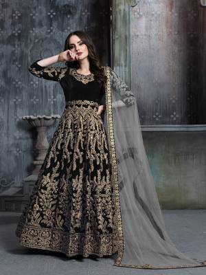 Get Ready For The Upcoming Wedding And Festive Season Wearing This Heavy Designer Floor Length Suit  In Black Color Paired With Grey Colored Dupatta. Its Heavy Embroidered Top Is Fabricated on Velvet Paired With Santoon Bottom And Net Fabricated Dupatta. 