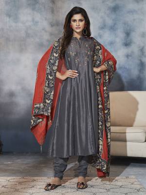 Here Is A Beautiful Readymade A-Line Patterned Suit To Add Into Your Wardrobe In Dark Grey Color Paired With Rust Orange Colored Dupatta. Its Top and Dupatta Are Muslin Fabricated Paired With Satin Based Chudidar. 
